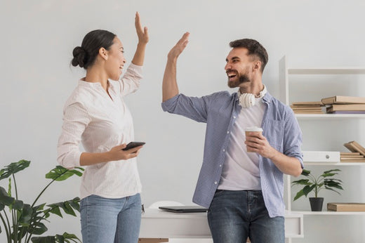 A woman and man in an office giving each other a high five.